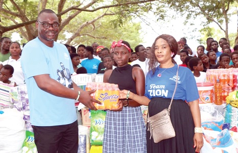 Apostle David Agyemang Badu (left), founder of God's Grace Royal Tabernacle, presenting an item to an inmate of the Village of Hope orphanage home
