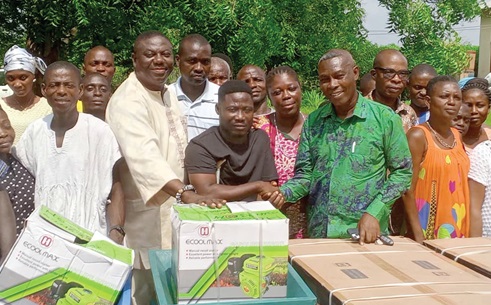 Alfred Eklu Odikro (2nd from right), Agotime-Ziope DCE, and Kingsley Sonu (2nd from left) presenting the items to Wisdom Yormekpe (middle), District Chairman of Agotime-Ziope PWDs, while PWDs and officials of the assembly look on