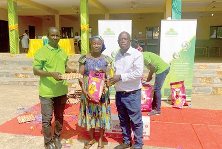 Two staff members of Ntiamoah Foundation presenting some of the items to one of the beneficiaries at Afosu.