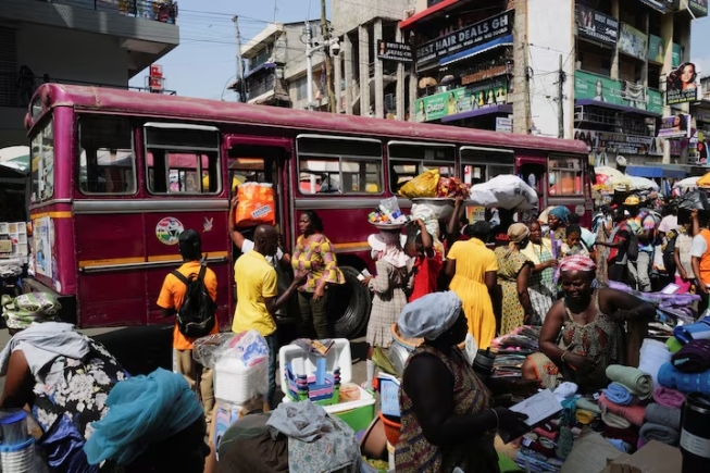 Traders sell goods along a busy street at Makola market in Accra, Ghana, December 6, 2025. REUTERS/Francis Kokoroko