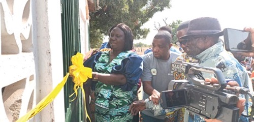 Ann Musah (left), Builsa South DCE, being supported by Samuel Larbi Agyarko (right), Zonal Coordinator of the SOCO Project for the Upper East and North East regions, and other officials to cut the tape to inaugurate one of the projects 