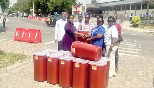 Dinah Brandful (2nd from right), Director of Operations, Rapid Courier, presenting the bins to Aimee Akotey (2nd from left), Director of Nursing Services, KBTH. Looking on are Adelaide Assan-Amoateng (right), Executive Partner, Rapid Courier; Dr Harry Akoto, Deputy Director, Medical Affairs, KBTH, and others