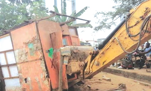  An excavator lifting a shop from  its original site