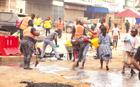 Personnel from Ghana Police Service, Zoomlion Ghana Limited, supported by community members, clearing silt and waste from sections of the road during the cleanup exercise at Accra Central