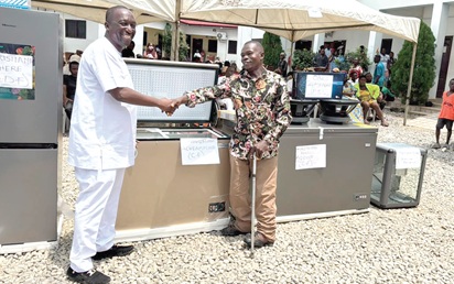 Kalamu Musah Adamu (left), MCE for Ablekuma North, presenting one of the items to a beneficiary  