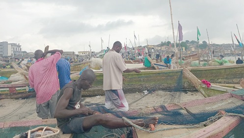 Fishermen mending their nets at the Cape Coast beach Fishermen mending their nets at the Cape Coast beach