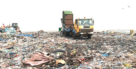 A waste disposal truck emptying a truck at the peak of the mountainous dumpsite