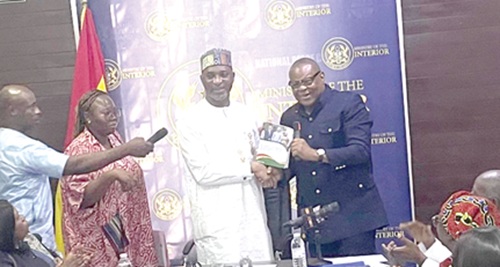 Emmanuel Habuka Bombande (right), Chairman of the committee, presenting the report to Muntaka Mohammed-Mubarak, the Minister for the Interior