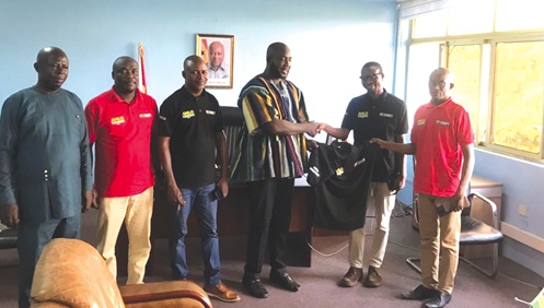 Kenneth Dzadu (2nd from right), CEO of KP Swift Services Limited, presenting a branded polo shirt to Wisdom Seade (3rd from right), Keta Municipal Chief Executive, during the meeting. Those with them are some executives of KP Swift Services Limited and officials of the assembly