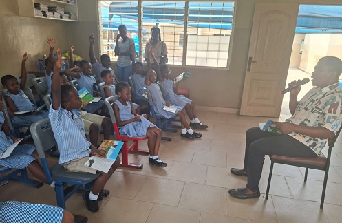 Mr Moses Abrokwa (right), a facilitator, guiding pupils to read a storybook in Twi.