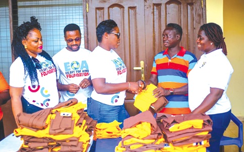Eugene Ofei Ansah (2nd from right), Founder of EOA Heart for Kids Foundation, handing over school uniform to Lydia Akortia (3rd from left), Headmistress, Panpanso Krokese M/A Basic School
