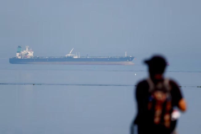 A tourist watches the MT Desert Kite oil tanker carrying Russian oil at Narara Marine National Park in the Arabian Sea, Gujarat, India, on March 11, 2026. Amit Dave/Reuters