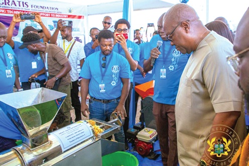 President John Dramani Mahama observing how a fruit juice extractor works during a tour of the exhibition