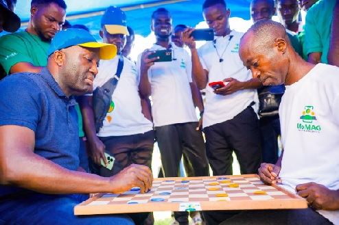 Shaibu Haruna (seated left), Mobile Money LTD CEO, engaged in hot draught contest against MoMAG President Edward Ofori Agyeman during the May Day Fun Games