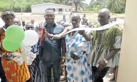 Jerry Yaw Ameko (3rd from right) being assisted by Togbe Asamoah IV (in cloth), Chief of Adaklu Ahunda-Boso, and Mathew Ayamba Adam, Adaklu District Director of Health, to cut the tape. INSET: The three-unit nurses’ quarters of the Adaklu Ahunda-Boso Health Centre