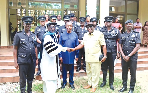 Monsignor Rev. Dr Alex Bobby Benson (in gown) in a handshake with Papa Owusu-Ankomah, former Attorney - General. With them are Francis Poku (middle), former National Security Coordinator, and other police personnel after the graduation ceremony at the St.Bakhita Parish Hall in Koforidua