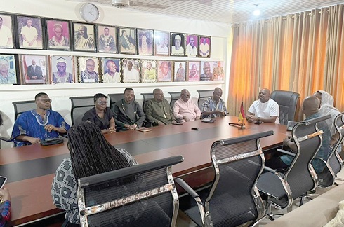 Members of the committee engaging with Charles Lwanga Puozuing (head of table), Upper West Regional Minister, before the tour. INSET: The uncompleted Wa Court Complex
