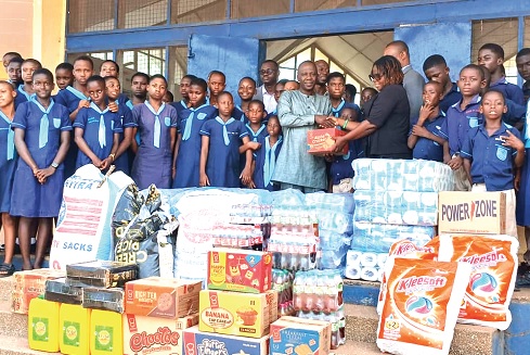 Professor Alex Asase (left), Executive Director of the Centre for Plant Medicine Research, presenting one of the items to Mabel Ofosu (right), Assistant Headmistress of Mampong School for the Deaf, while the children look on