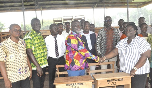 Nufialaga Mawufemor Korbla Nornyibey (arrowed), Mawuli School PTA chairman, presenting the desks to Patricia Awo Kodjo, an assistant headmistress of the school