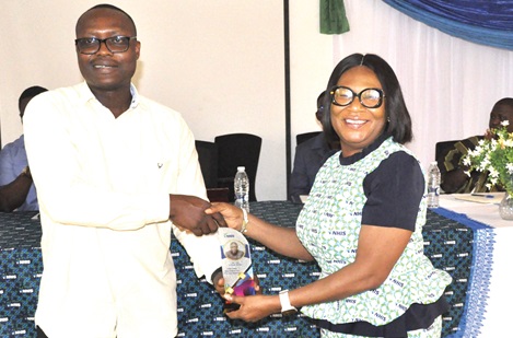 Yanick Noah Agboado, Assistant Director of VRCC, receiving a plaque on behalf of the Volta Regional Minister, James Gunu, from Susan Chobbah, Volta Regional Director, NHIA