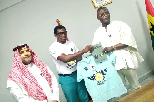 Mr Aduba Iloba Noel (middle) presenting a PGMF shirt to Kofi Adams, Minister of Sports and Recreation while Dr Al Dosari looks on