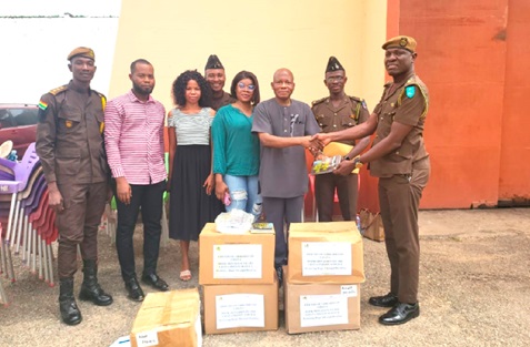Peter Anafo (3rd from right) presenting a copy of a book to DPP Patrick Thomas Seidu of the Nsawam Prisons. With them are other officers and officials of FOLIG
