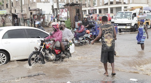 Pedestrians and motorists battling flooded roads at Darkuman Junction as rains expose the recurring drainage challenges in parts of Accra. Picture: CALEB VANDERPUYE