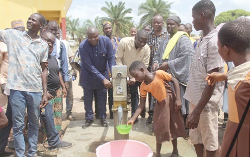 A pupil of Shalom and Agape KG and Primary School at Kpassa, one of the beneficiaries schools fetching water from the borehole. With her is Isaiah Dordoe, (arrowed) DCE, Nkwanta North