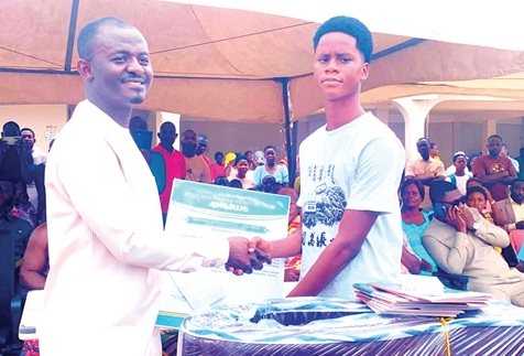 Charles Akwasi Asiedu (left), Tano South MP, presenting a citation and education support packages to Benjamin Ayitey Ajavon, Overall best BECE graduate in the municipality