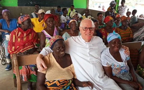 Fr. Andrew Campbell seated with persons suffering from leprosy 