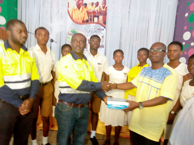 Nana Ampofo Bekoe (left), the Sustainability Manager of the AGA,  presenting some of the books to Mr Kwabena Sarpong, the Headmaster of the Obuasi Secondary Technical School. Looking on are some of the students.