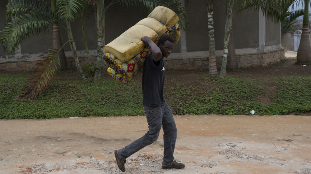 A student carries his bedding from a tent where he has taken refuge with hundreds of other students [Phil Moore/Al Jazeera]