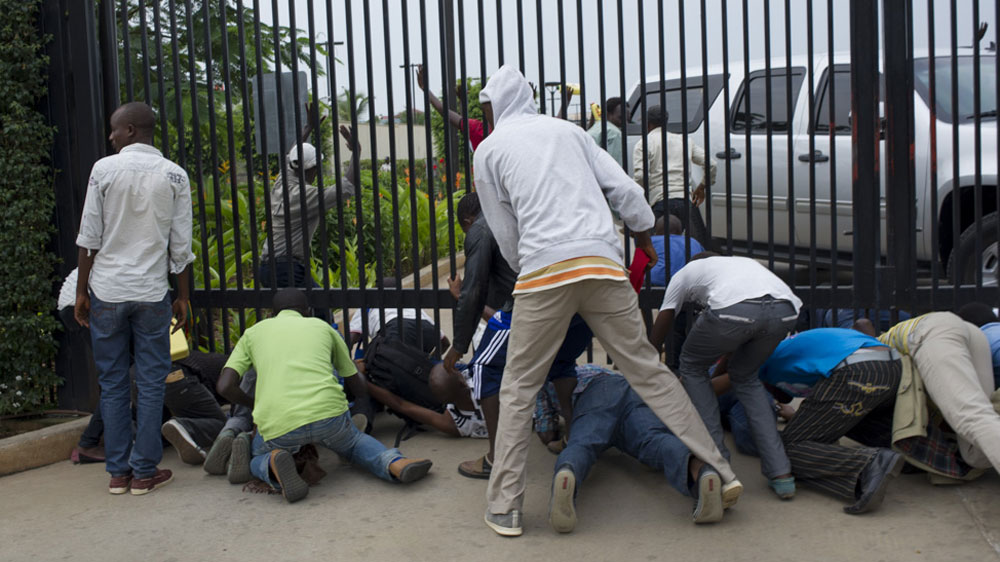 Students rush under the gate to the US embassy as police arrive to forcibly remove them [Phil Moore/Al Jazeera]