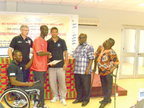 A participant receiving a certificate from one of the course experts. with them at the far right is Disabled Sports president Adja-Cofie and his vice, Adjetey Sowah