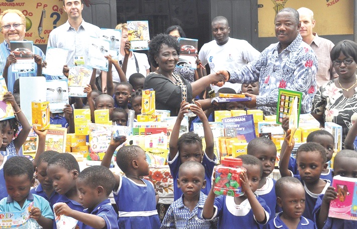 Mr Kwamena Anderson (second right), Head of Organisation and Administration of GNAT, presenting the items to Ms Elizabeth Attokora (middle), Head of the kindergarten.