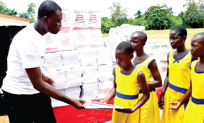 Mr Kofi Akyea, Senior Marketing Executive of MoneyGram, presenting a copy of the Junior Graphic to one of the beneficiaries.