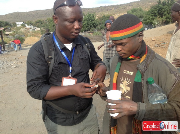 Charles, (right) a miner shows Moses Aklorbortu (the writer) his find.