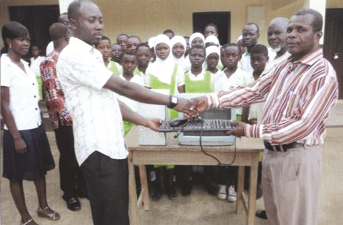 Mr Asumadu Addae (left) presenting the computer to Mr Odame-Addo. Others in the picture are the staff and pupils of the school