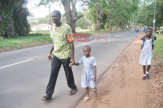 • A desperate parent walks with his daughter to the University Primary School, while another pupil follows them dejectedly. Picture: SAMUEL TEI ADANO