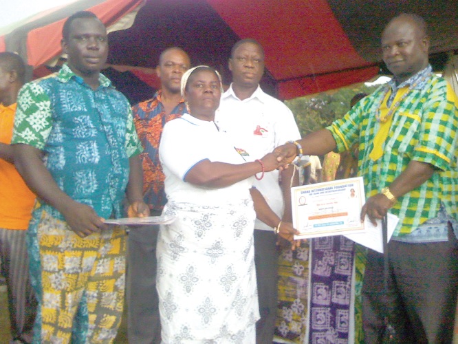 Nana Louis Akattah, the District Chief Executive for Biakoye (right), presenting a certificate to Madam Grace Teye (middle), one of the participants, while Mr Daniel Antwi, Director of GIFTE (left) looks on.