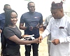Doreen Klutse (left) in a handshake with Samuel Okudzeto Ablakwa (right), the Minister of Foreign Affairs, after receiving her passport at the Ghana Library Authority head office in Accra, as officials from Ghana Post look on