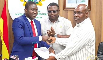 Maxwell Y. A. Klu (left), Chairman of the Tender Committee on the Damang Mines, presenting the evaluation report to Innocent Haligah (right), Chief Director of the Ministry of Lands and Natural Resources, during the event 