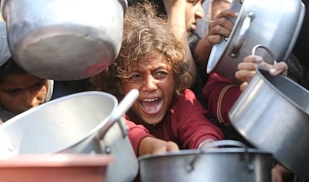 A child reacts surrounded by pots as Palestinians wait to receive food from a charity kitchen in Khan Younis, southern Gaza Strip, August 21, 2025. REUTERS/Hatem Khaled