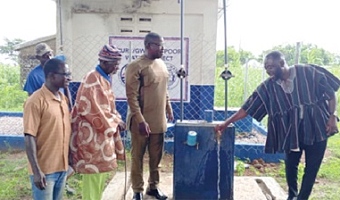 Seth Kponyo (right), PURC Regional Manager, opening the tap for water to flow from one of the boreholes, while Joseph Akaseje Abaa (2nd from right), Bongo DCE, and other guests look on
