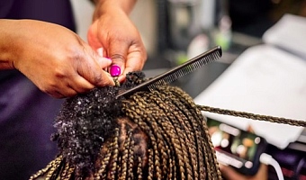 A hairstylist uses hair extensions to braid a client's hair. NickyLloyd/E+/Getty Images