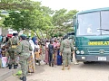Immigration officers assisting beggars onto waiting buses as they clear them from the city