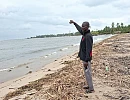 Noah Aggrey, a fisherman, pointing far away to where the shoreline used to be