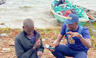 Daily Graphic's Timothy Ngnenbe interacting with Noah Aggrey as he mends his net at the shores of Azizape Island.