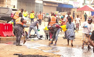 Personnel from Ghana Police Service, Zoomlion Ghana Limited, supported by community members, clearing silt and waste from sections of the road during the cleanup exercise at Accra Central