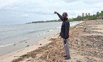 Noah Aggrey, a fisherman, pointing far away to where the shoreline used to be